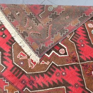 Puede incluir: Una alfombra roja y marr&oacute;n con patrones y flecos en los bordes. La alfombra tiene un dise&ntilde;o geom&eacute;trico con detalles intrincados.