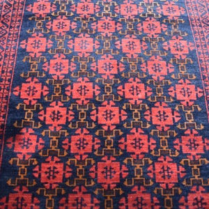 May include: A red, blue, and brown patterned rug with a geometric design. The rug has a border with a repeating pattern.