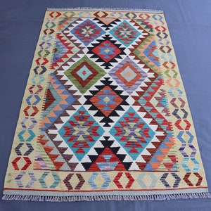 May include: A colorful rug with a geometric pattern in shades of red, blue, green, and white. The rug has a fringe border.