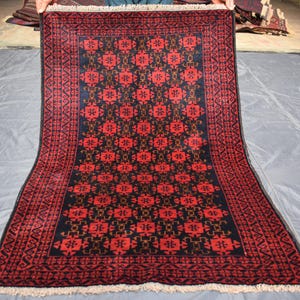 May include: A red and black rug with a geometric pattern. The rug has a fringe border.
