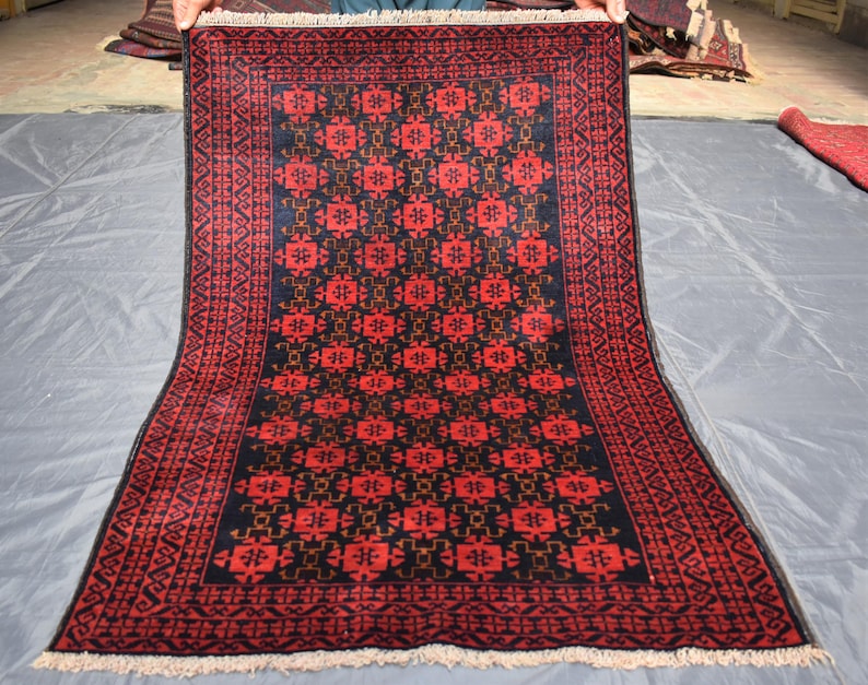 May include: A red and black rug with a geometric pattern. The rug has a fringe border.