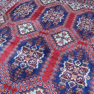 Può includere: Un tappeto persiano tradizionale con un motivo geometrico rosso, blu e bianco. Il tappeto ha un design dettagliato con dettagli intricati.