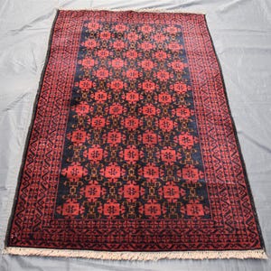 May include: A traditional Persian rug with a dark blue background and a red and gold geometric pattern. The rug has a fringe border.