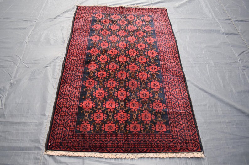 May include: A traditional Persian rug with a dark blue background and a red and gold geometric pattern. The rug has a fringe border.