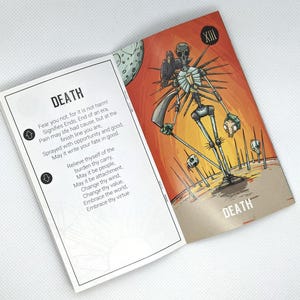 May include: An open tarot card spread featuring the Death card. The card has a skeletal figure with a gas mask and a bird on its shoulder, set against an orange and brown background. The card's text reads "DEATH" and includes a poem.