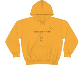 Könnte beinhalten: Gelber Hoodie mit einem schwarzen Aufdruck, der "Different Than Most" mit einer Taube und einem Grafikmotiv von betenden Händen sagt. Der Text "John 17:15-21" ist ebenfalls auf dem Hoodie gedruckt.