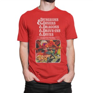 May include: Red t-shirt with a white graphic of a Dungeons & Diners & Dragons & Drive-Ins & Dives parody game cover. The cover features a red dragon with a knight fighting it. The text on the cover reads "Escape From Flavortown."