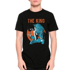 May include: Black t-shirt with a vintage-style graphic of Elvis Presley in a blue suit, with the text "THE KING" in orange above him.
