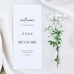 May include: A white wedding invitation card with black text. The text reads "welcome to the wedding of Anna + Benjamin The Hilton Hotel San Diego, CA 07.18.25"