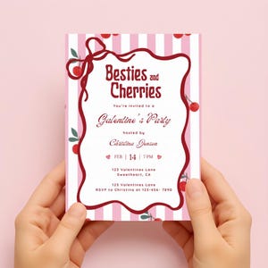 以下が含まれることがあります： 「Besties and Cherries」と「Galentine's Party」の文字が入った、ピンクと白のストライプの招待状。 さくらんぼと装飾的なボーダーで飾られています。 招待状はクリスティーナ・ジェンソンが主催しています。