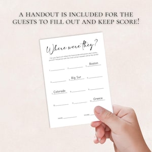 May include: A white card with the text "Where were they?" is held by a hand. The card includes fill-in-the-blank questions with locations like Boston, Big Sur, Colorado, and Greece. The text "A handout is included for the guests to fill out and keep score!" is at the top.