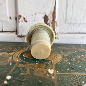 Puede incluir: Un tap&oacute;n de botella vintage en beige claro y blanquecino. El cuerpo cil&iacute;ndrico y la parte superior circular sugieren que est&aacute; hecho de pl&aacute;stico o un material similar. El dise&ntilde;o es simple y funcional, para sellar botellas.