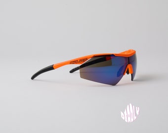 Puede incluir: Gafas de sol de ciclismo naranja y negro con lentes azules espejados. Las gafas tienen la palabra "SALICE" impresa en la montura.