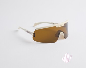 Puede incluir: Gafas de sol con montura blanca y lentes marrones con la palabra "SCOTT" impresa en el lateral.