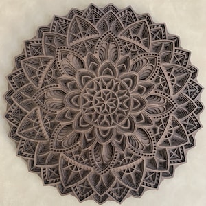 May include: A brown wooden mandala with intricate geometric patterns and layered designs. The mandala is circular and has a symmetrical design.
