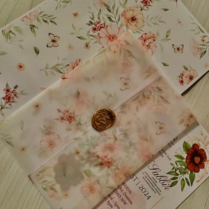 Puede incluir: Una invitación con estampado floral y un sello de cera. La invitación es para una recepción de boda para Sabbir. La recepción se celebrará el 1 de julio de 2024 en The Ardens, 1 Rd, Dunton, CM13 3SW. La recepción comenzará a las 5 pm y terminará a las 8 pm. La invitación indica "no se aceptan regalos en caja".