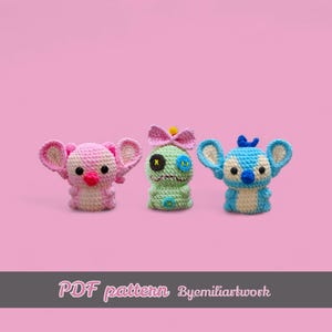 May include: Three colourful crochet figures in pink, green, and blue, each with large ears and unique details. The pink figure has a bow and a red nose. The green figure has a bow and a stitched eye. The blue figure has a small crown. The text "PDF pattern Byemiliartwork" is at the bottom.