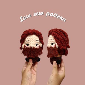 May include: Two crochet figures of a bearded man with red hair and beard, and a cream-colored face. The figures are held up against a pink background. The text "Low sew pattern" is written in white cursive above the figures.