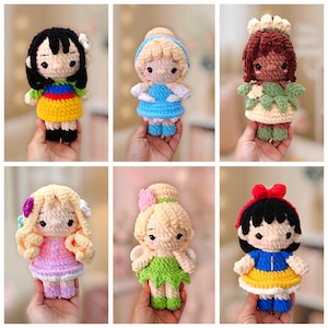 May include: A collection of six handmade crochet dolls featuring various characters with distinct yarn colors, including black, blonde, and brown hair, wearing colorful outfits like blue, yellow, green, and pink dresses with detailed yarn textures.