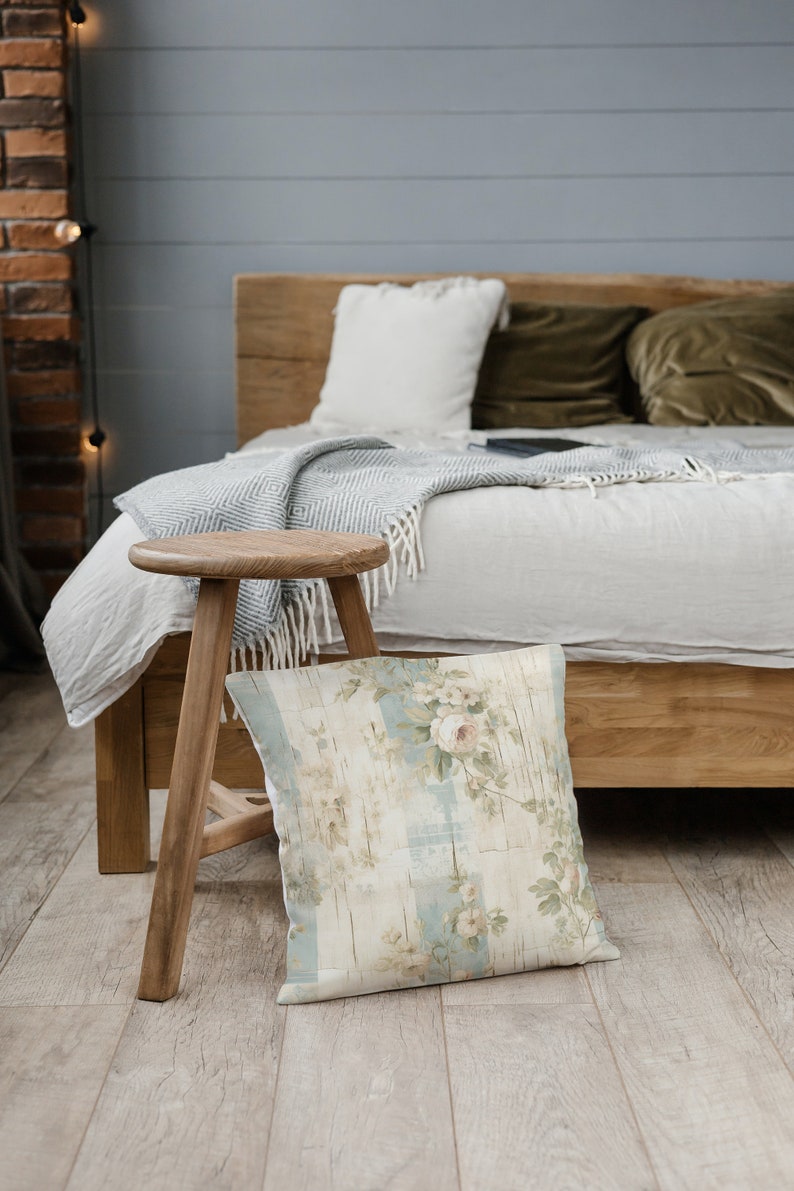 May include: A wooden stool with a floral patterned pillow sitting in front of a bed with a white blanket and green pillows.