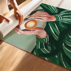 May include: A close-up of a person holding a cup of coffee with a green and white striped shirt. The coffee is in a white ceramic cup with a brown rim.