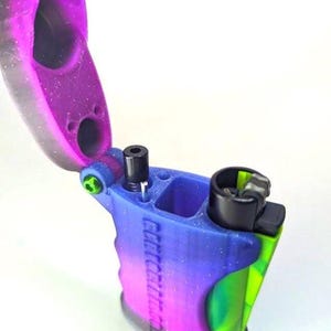 May include: A multi-colored, handheld device with a hinged lid. The device features a gradient of blue, purple, and green hues. The text "Gettitright" is visible on the side. The lid is open, revealing internal components.
