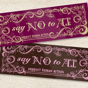 May include: Two rectangular stickers with ornate floral borders. The top sticker is a deep magenta with gold accents and the text "say NO to AI, support human artists." The bottom sticker is brown with pink accents and the same text.
