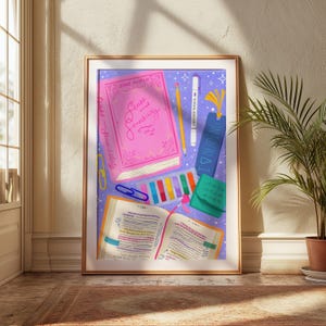 May include: A framed print featuring a collection of reading-related items. A pink book titled "Sense and Sensibility" is next to an open book with highlighted text. Other items include a pencil, highlighter, bookmark, and colorful sticky notes.