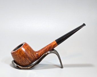 Op de afbeelding: Een bruine houten pijp met een zwarte steel die op een zilveren standaard rust. De pijp heeft een natuurlijk houtnerfpatroon.