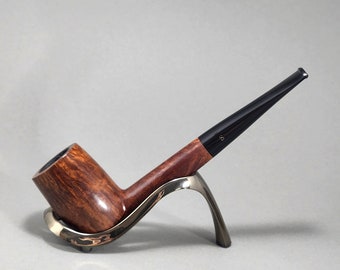 May include: A brown wooden pipe with a black stem resting on a silver stand.