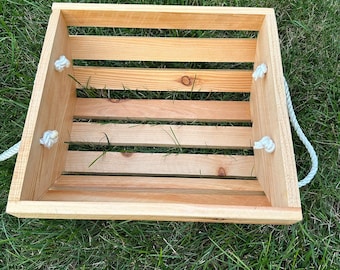 May include: A natural wood crate with rope handles. The crate is empty and has a rustic look.