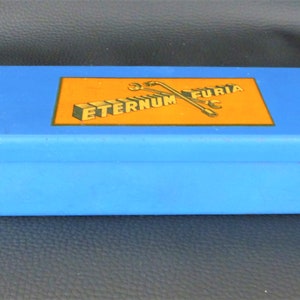 May include: A blue rectangular box with a yellow label that reads "ETERNUM FURIA" with a graphic of two crossed keys.