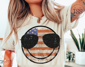 May include: A white t-shirt with a distressed American flag design in the shape of a smiley face wearing sunglasses.