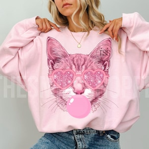 Chat soufflant des bulles png Chat PNG Mascotte de chat PNG Preppy Mascotte Preppy PNG Coeur rose pailleté Chemise chat preppy Design par sublimation