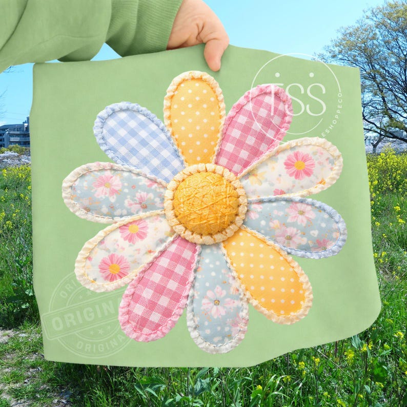 May include: A large, colorful daisy applique on a light green background. The daisy petals are patchwork in various patterns, including gingham, polka dots, and floral prints. The center of the flower is a textured, yellow circle.
