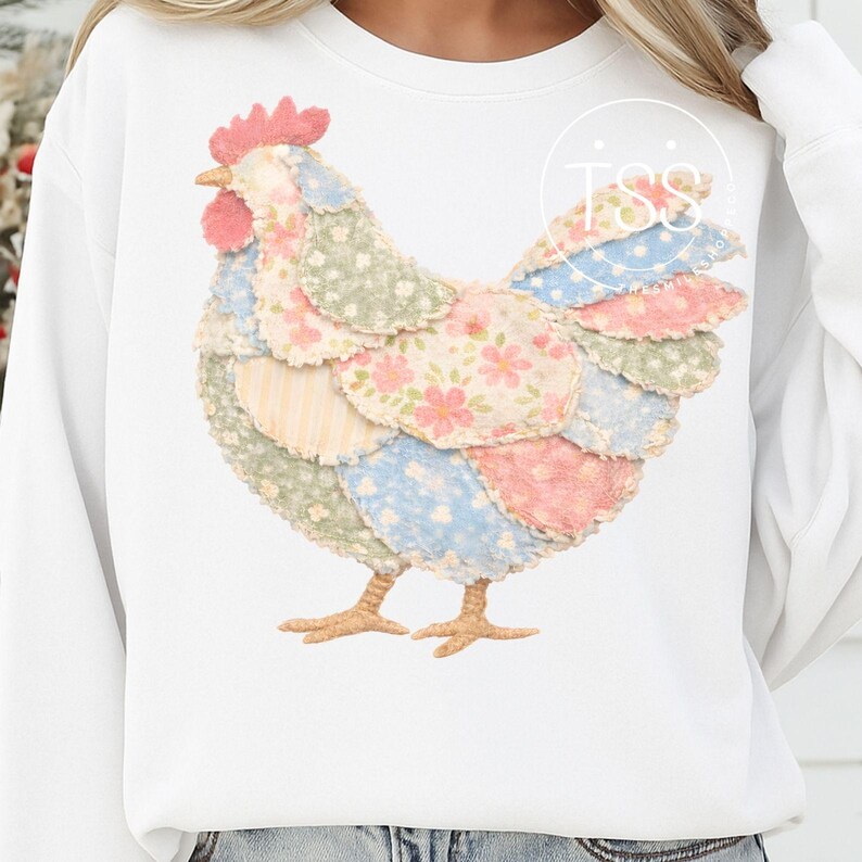 May include: White sweatshirt featuring a colorful patchwork chicken design. The chicken has a red comb, yellow beak, and is composed of various fabric patches in pastel colors, including pink, blue, and green floral patterns. The design is centered on the front of the shirt.