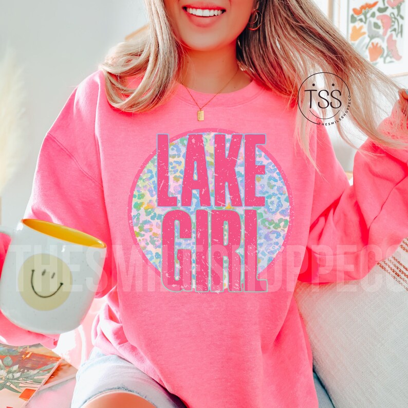 May include: Pink sweatshirt with a circle graphic that says "LAKE GIRL" in pink letters with a distressed look. The circle graphic has a blue, pink, and green leopard print.