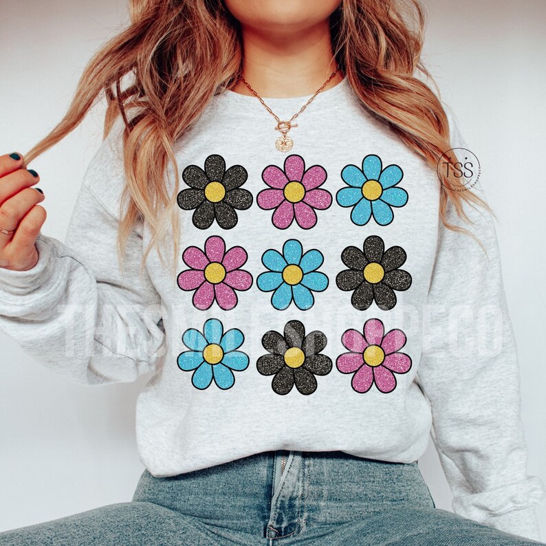 May include: A gray sweatshirt with a pattern of nine glittery flowers in black, pink, and blue. The flowers are arranged in three rows of three.