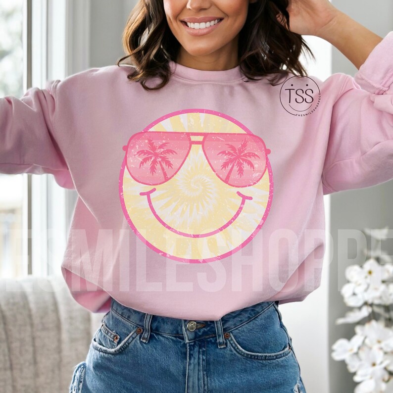 May include: Pink sweatshirt with a tie-dye smiley face wearing pink sunglasses with palm trees reflected in the lenses. The text "TSS" is visible in the upper right corner of the image.