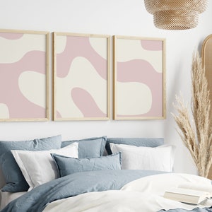May include: Three framed abstract art prints with a pink and cream color scheme. The prints feature organic shapes and lines.