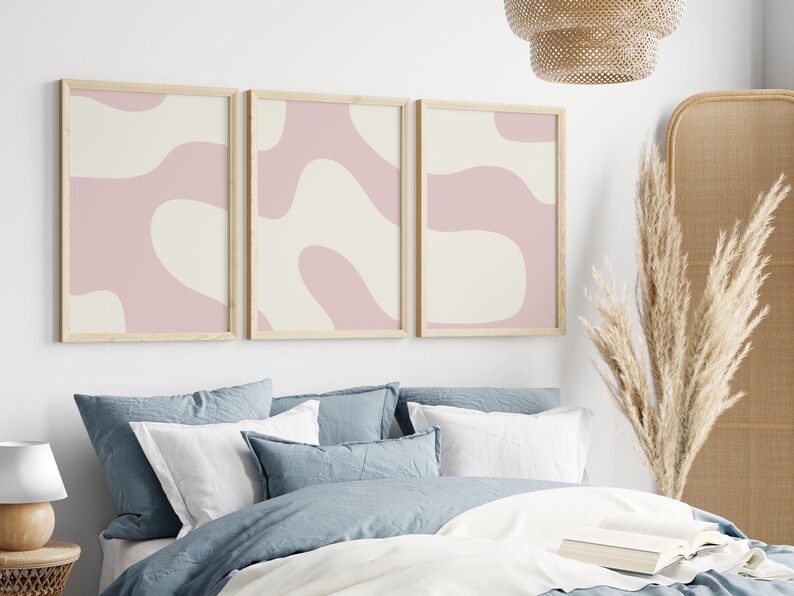 May include: Three framed abstract art prints with a pink and cream color scheme. The prints feature organic shapes and lines.