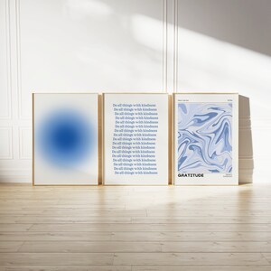 Op de afbeelding: Drie ingelijste prints met een abstract ontwerp in blauw en wit. De middelste print heeft de tekst "Do all things with kindness" 17 keer herhaald. De rechter print heeft de tekst "GRATITUDE".