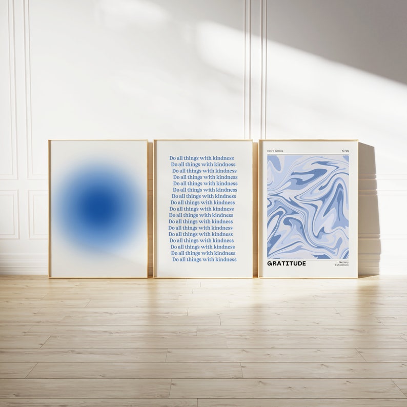 Op de afbeelding: Drie ingelijste prints met een abstract ontwerp in blauw en wit. De middelste print heeft de tekst "Do all things with kindness" 17 keer herhaald. De rechter print heeft de tekst "GRATITUDE".