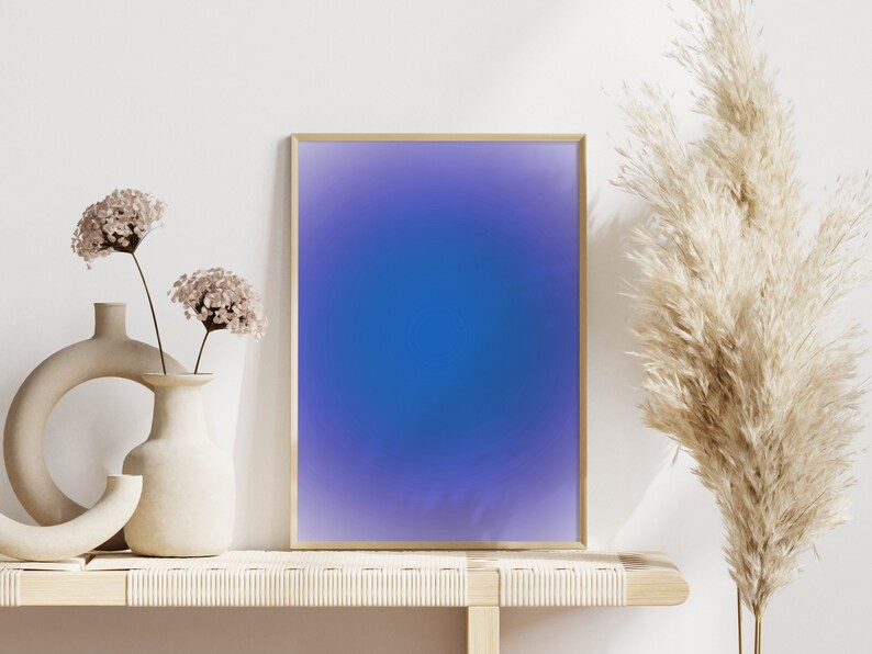 Peut inclure: Une impression abstraite encadr&eacute;e avec un d&eacute;grad&eacute; de couleurs violettes et bleues. L'impression est expos&eacute;e sur une &eacute;tag&egrave;re en bois clair avec deux vases de fleurs s&eacute;ch&eacute;es et une plante de gramin&eacute;es s&eacute;ch&eacute;es.
