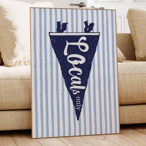 Op de afbeelding: Een blauw-wit gestreept vlaggetje met de tekst "Locals only" in witte cursieve letters. Het vlaggetje hangt aan een muur met een witte achtergrond.