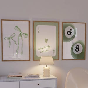 May include: Three framed art prints in light green and white. One shows a watercolour bow, another a playing card, and the third, two eight-balls. The text "How lucky are we?" is on the playing card print.