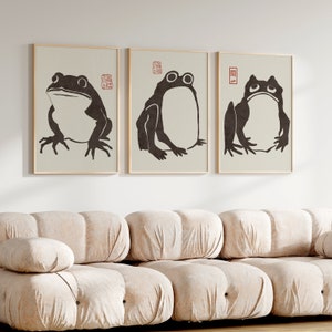 May include: Three framed black and white illustrations of frogs. Each illustration features a different frog pose. The frames are light brown wood with a white mat.