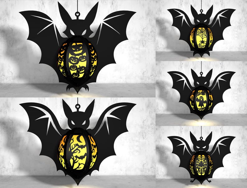 May include: Five black bat-shaped paper lanterns with different designs. Each lantern has a round, yellow, and orange paper sphere with a different cut-out design. The designs include a spiderweb, a ghost, a tree, a jack-o-lantern, and a spiderweb.