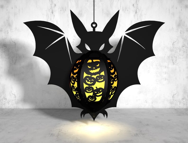 May include: A black bat silhouette with a hanging, round, orange and yellow pumpkin-shaped lantern. The lantern has a black outline and is filled with smaller pumpkin faces.