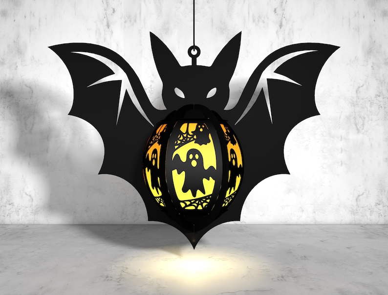 May include: A black bat silhouette with a glowing orange and yellow sphere hanging from it. The sphere is decorated with a spiderweb design and several ghost figures.